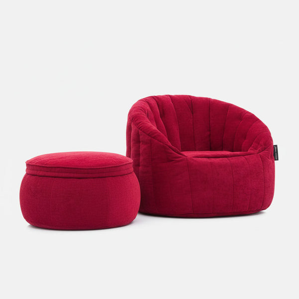 En plysset, dybrød lænestol med afrundet ryg og en matchende Memory Foam Ottoman, begge betrukket med blødt stof, står på en almindelig hvid baggrund.