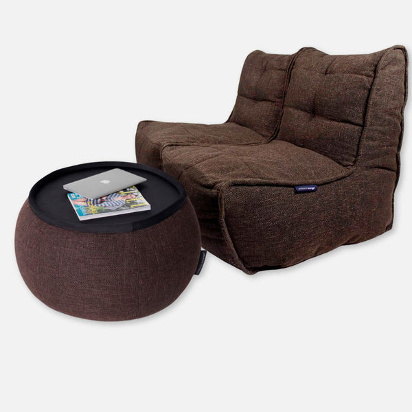 En brun, polstret Twin Couch to-personers sofa med et matchende rundt ottomanbord. Det fleksible møbler-design er ideelt til SOHO-pakken og har en flad, sort bakke på ottomanen, der kan rumme en lukket laptop og et magasin med blød stofstruktur.