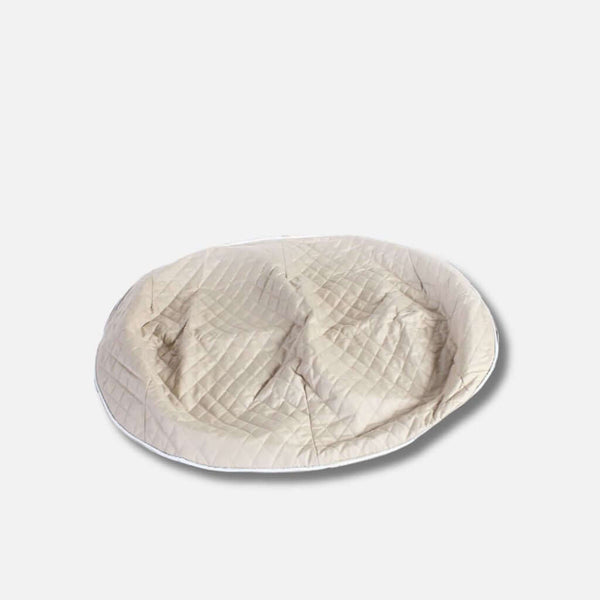 En stor, rund, beige ThermoQuilt hundeseng med quiltet topptrekk og en let indrykket midte, perfekt som allergivennlig hundeseng. Placeret på en almindelig hvid baggrund.