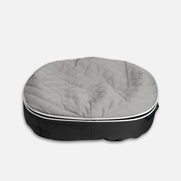 En rund, grå ThermoQuilt-hundeseng med en polstret top og en mørkere grå stofbase på en almindelig lys baggrund.