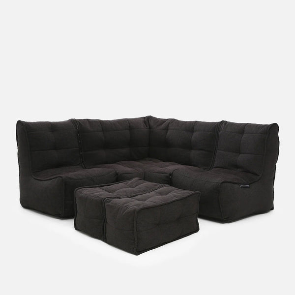 En moderne sort hjørnesofa med tykke, tuftede puder og to matchende firkantede ottomaner, alt sammen på en enkel hvid baggrund.