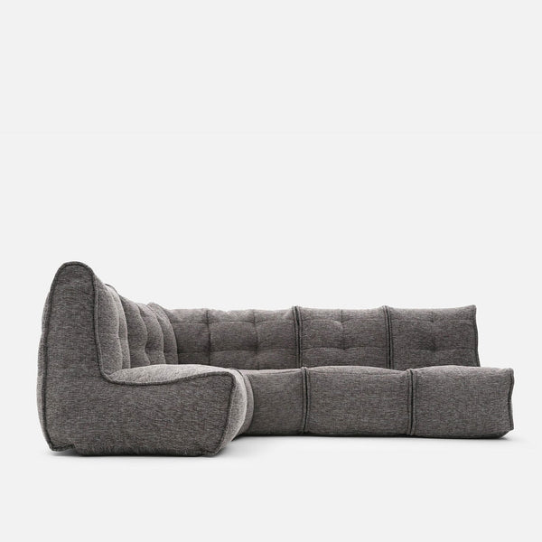 En moderne, modulopbygget grå Ambient Lounge Mod 4 L-sofa med tuftede hynder og et lavt, armløst design giver fleksible møbleringsmuligheder på en almindelig hvid baggrund.