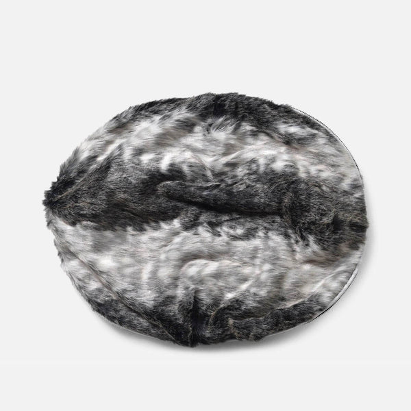 En rund, plysset hundeseng med en luksuriøs pelstopp og blød fuskepelstrekk i grå, sorte og hvide nuancer, der ligner dyrepels, mod en almindelig hvid baggrund.