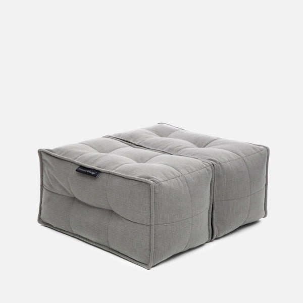 En firkantet, grå, tuftet gulvpude eller designerpuf med synlige sømlinjer og blød stofstruktur på en almindelig hvid baggrund - perfekt til ethvert Ambient Lounge-miljø.