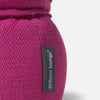 Nærbillede af en sækkestol i magentafarvet stof med en sort, lodret etiket med teksten ambient lounge® syet på siden. Den er designet til komfort og har en pude af memory-skum. Baggrunden er ensfarvet og lys.