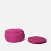 En rund magenta meditationspude ligger ved siden af to stablede matchende Memory Foam-puder, alt sammen på en almindelig hvid baggrund.