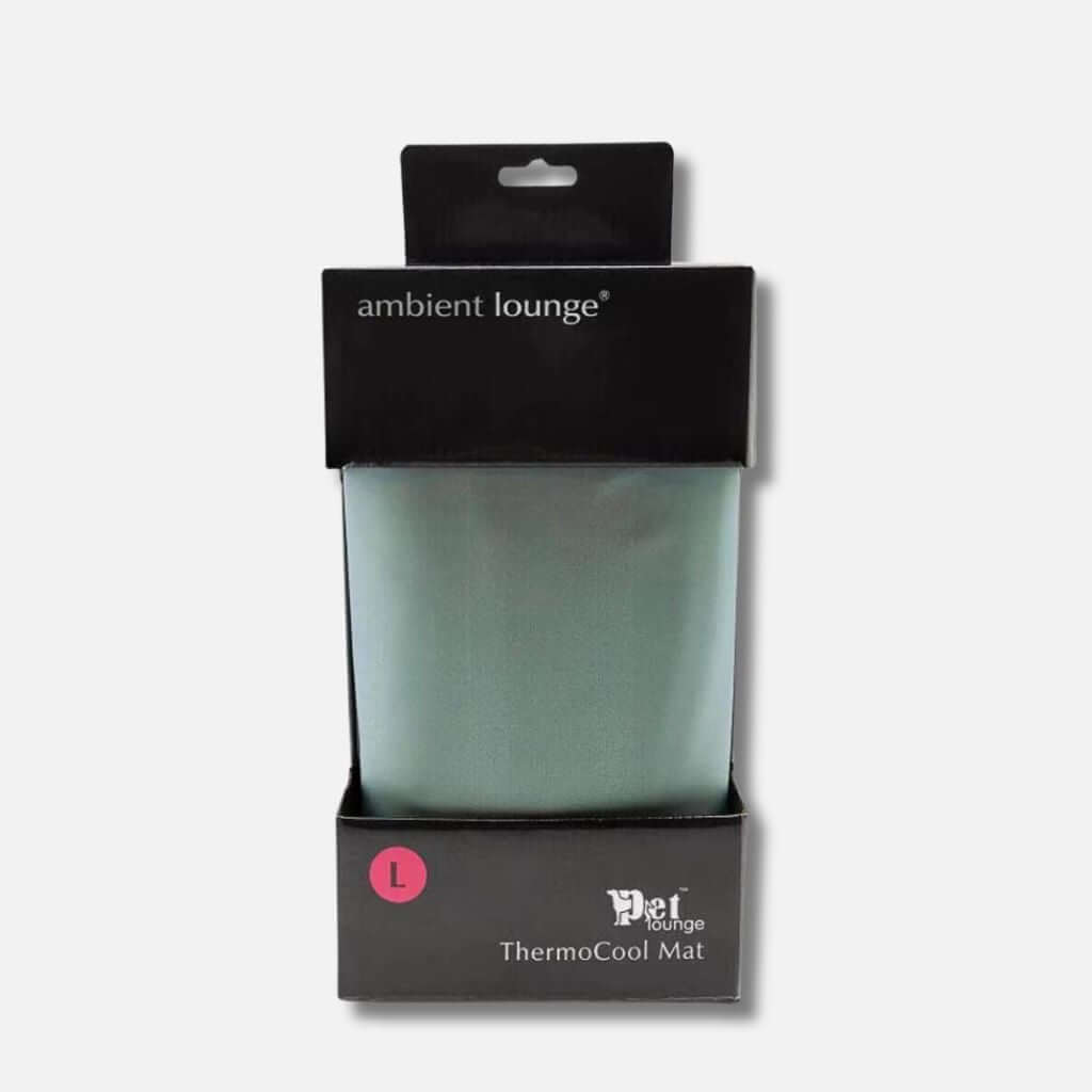 En pakket Ambient Lounge ThermoCool Mat, perfekt som en kølemåtte til hund eller hundeseng, i størrelse large. Præsenteret i en elegant sort æske med branding og en pink L-label på forsiden. Den lysegrønne måtte er synlig indeni.