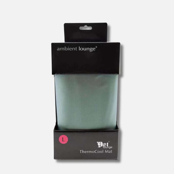En pakket Ambient Lounge ThermoCool Mat, perfekt som en kølemåtte til hund eller hundeseng, i størrelse large. Præsenteret i en elegant sort æske med branding og en pink L-label på forsiden. Den lysegrønne måtte er synlig indeni.